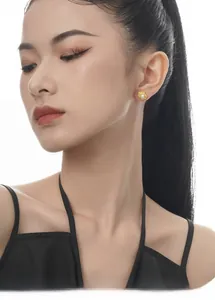 Detailaufnahme der goldenen Blumen-Ohrstecker mit Perle und Hammerschlag-Optik am Model