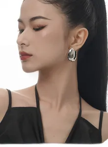 Macro view of oversized irregular polished S925 sterling silver studs on a model