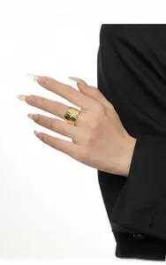 Detailed view of chunky gold starburst ring featuring engraved cross motifs on model finger