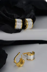Detail of two-tone C-shape earrings with gold mirror finish and silver hammered texture