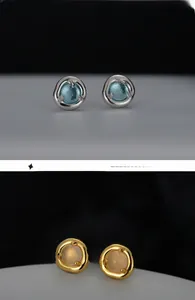 Close-up of 925 silver and gold earrings with blue crystal and white agate stones
