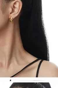 Eleganter vergoldeter U-Ohrring mit weißer Perle, getragen von einem Modell auf weißem Grund