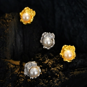Elegante unregelmäßig strukturierte Silber Perlenohrringe in Gold und Silber auf Holz