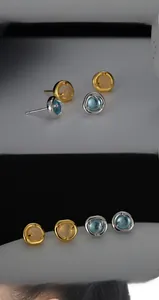 Detailed view of silver and gold irregular lava earrings with white agate and blue crystals