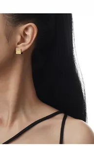 Macro view of square gold-plated S925 silver earrings with vintage floral engravings