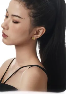 Close-up of elegant gold square earrings with intricate hollow pattern on a female model