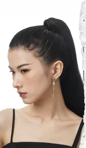 Close-up of elegant two-tone tassel earrings with baroque pearls worn by a model