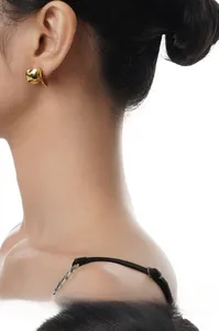 Dettaglio di un orecchino dorato irregolare in stile lava indossato da una modella