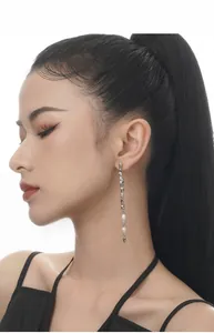 Detail of silver textured long drop earrings with freshwater pearls on a model side profile