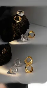 Détail de boucles d'oreilles géométriques en argent avec texture fluide dorée et argentée