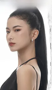 Detail of silver drop earrings with white zircons and black enamel on model ear