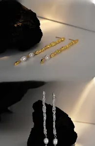 Detail showing asymmetric textured lava metal earrings with hanging freshwater pearls