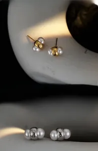 Detailed view of freshwater pearl stud earrings with textured hammer patterns in gold and silver