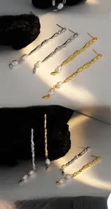 Detail of asymmetric textured silver earrings with freshwater pearls in gold and silver