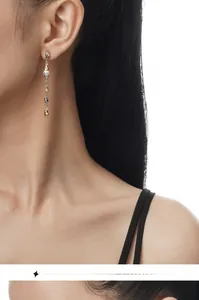 Detail of elegant two-tone drop earrings with Baroque pearls on model's ear