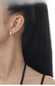 Close-up of gold hoop earrings with black and white zircon on model ear