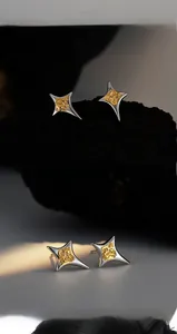 Close-up of four-pointed star earrings with silver edges and golden lava texture