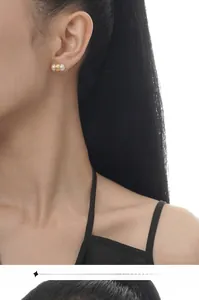 Detail of freshwater pearl stud earring with textured gold ring on a female model