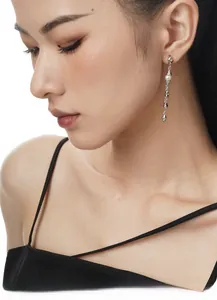 Detail of long S925 silver chain earrings featuring white pearls and irregular metal charms