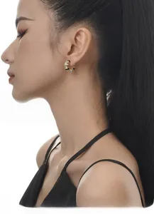 Close-up of model wearing black and white enamel hoop earrings with gold base and zircons