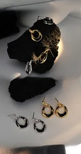 Vue macro de boucles d'oreilles ovales irrégulières en émail noir et finition dorée