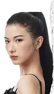 Close-up of minimalist silver hoop earrings on a model with artistic white background