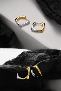 Close-up of dual-tone S925 sterling silver geometric earrings with metal hallmark