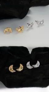 Macro shot of irregular moon stud earrings with colorful zircons and textured finish