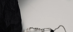 Gros plan d'un fermoir mousqueton en argent S925 et perles sur collier élégant