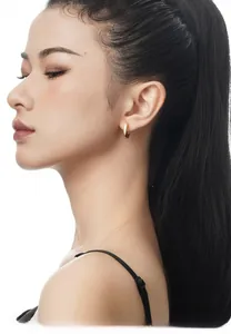 Close-up of elegant minimalist gold hoop earring worn by a model on white background