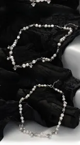 Detailed macro shot of irregular baroque pearl necklace with silver bee and flower charms