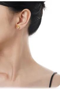 Close-up of a gold geometric stud earring with a square zircon on a female model