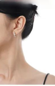 Detail view of sparkly S925 sterling silver triple star earrings on model ear