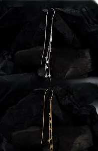 Macro view of gold and silver S925 long tassel earrings with sparkling cubic zirconia