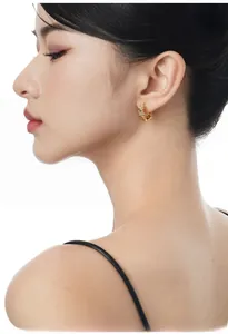 Close-up of star-shaped gold earrings with sparkling zircon stones worn by a model