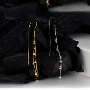 Detail view of gold and silver S925 sterling silver tassel earrings with sparkling cubic zirconia