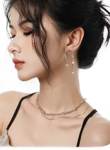 Détail de boucles d'oreilles en argent S925 et collier à perles sur modèle