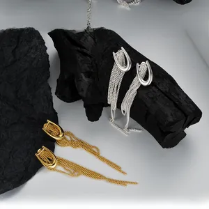 Detailed close-up of U-shaped silver and gold tassel earrings on a textured background