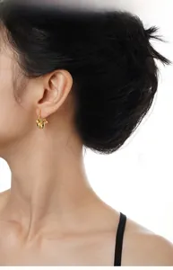 Detail of irregular C-shape gold lava earrings on model with minimalist aesthetic