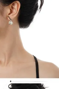 Close-up of minimalist S925 silver leaf earrings with glossy pearls worn by a model
