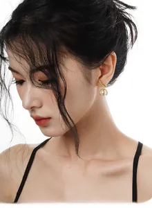 Elegant gold leaf-shaped stud earrings with round white pearls shown on female model