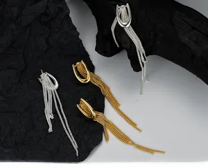 Detailed view of U-shaped gold and silver tassel drop earrings on minimalist dark background