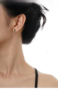 Close-up of S925 silver hoop earrings with engraved texture and green rectangle gemstone