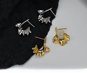 Macro detail of irregular C-shaped lava texture stud earrings in gold and silver