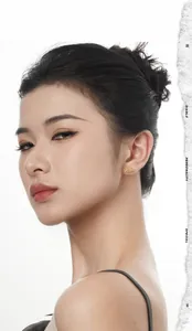 Detail of a gold planet-shaped stud earring with a lava texture on a model's ear