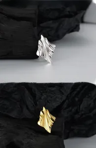 Macro detail of wave texture on irregular S925 silver and gold-plated hoop earrings