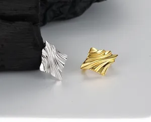Detailed view of S925 sterling silver hoop earrings with irregular wave textures in gold and silver