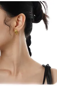 Detail of a minimalist gold wavy irregular textured earring worn by a model in profile