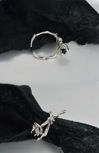 Macro detail of silver rose ring with thorn vine band and black gemstone center