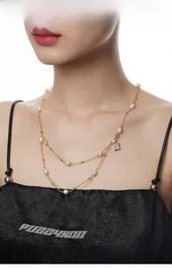Detail of layered S925 silver necklace with baroque pearls and zircon pendant on model